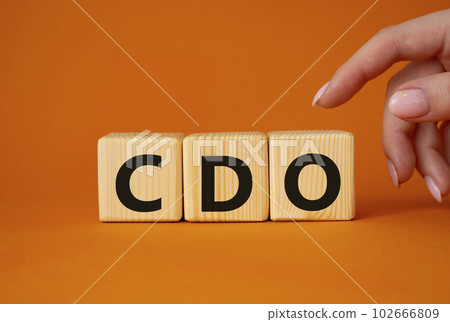 CDO - Collateralized Debt Obligation symbol. Wooden cubes with word CDO. Beautiful orange background. Businessman hand. Business and Collateralized Debt Obligation concept. Copy space. CDO - Collateralized Debt Obligation symbol. Wooden cubes with word CDO. Beautiful orange background. Businessman hand. Business and Collateralized Debt Obligation concept. Copy space. 102666809