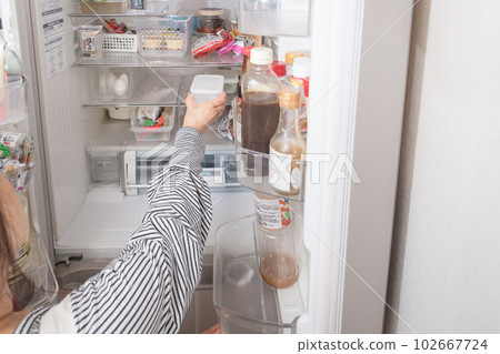 [A housewife taking out a tapper from the refrigerator] 102667724