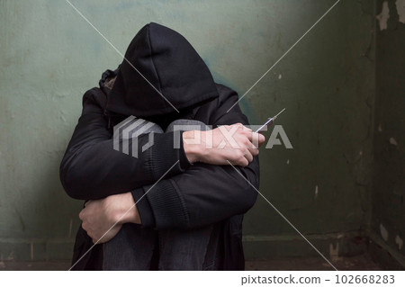 Addiction concept. Close-up of a young drug addict with a closed face in an abandoned house Addiction concept. Close-up of a young drug addict with a closed face in an abandoned house 102668283