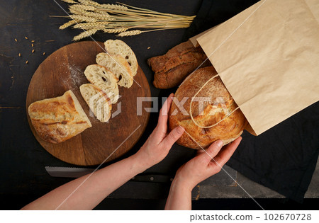The healthy eating and traditional bakery concept. Top viev. Fresh bread on table close-up. Fresh bread on the kitchen table Whole grain bread put on kitchen wood plate with a chef near knife ready 102670728