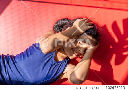 Little girl with a swimsuit is receiving the sun with direct light. 102672613