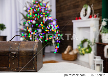 A brown old box in the foreground and a Christmas tree with Christmas lights in the background. A brown old box in the foreground and a Christmas tree with Christmas lights in the background. 102672894