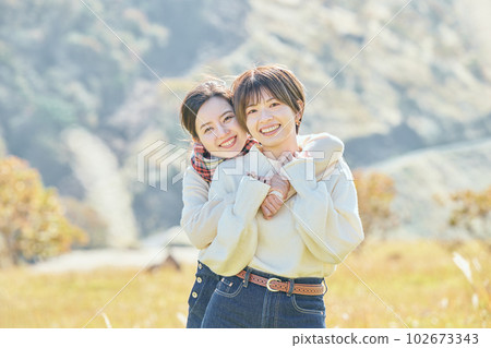 年輕女子和朋友在草地上從後面擁抱 102673343