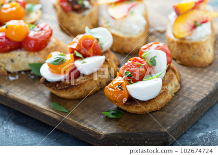 Crostini or bruschetta board with caprese made with roasted tomatoes Crostini or bruschetta board with caprese made with roasted tomatoes 102674724