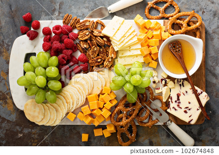 Cheese and snacks platter with honey and fresh fruit Cheese and snacks platter with honey and fresh fruit 102674848