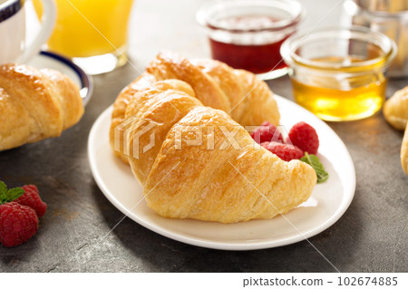 Freshly baked croissants with honey and jam Freshly baked croissants with honey and jam 102674885