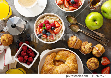 Breakfast table with oatmeal porridge, croissants and muffins Breakfast table with oatmeal porridge, croissants and muffins 102675258