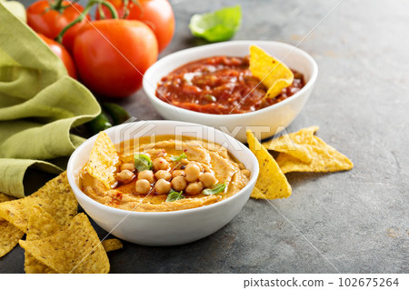 Homemade hummus and tomato salsa in white bowls with chips 102675264