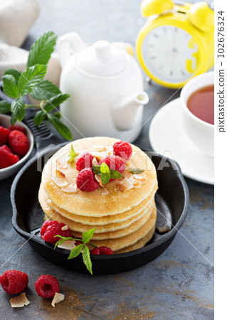 Stack of fluffy buttermilk pancakes with raspberry and coconut Stack of fluffy buttermilk pancakes with raspberry and coconut 102676324