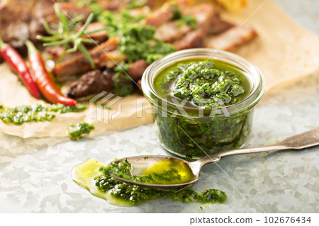 Green chimichurri sauce with grilled steak 102676434