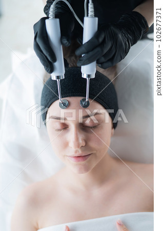 Young caucasian woman on microcurrent therapy procedure. Beautician's office. Young caucasian woman on microcurrent therapy procedure. Beautician's office. 102677371