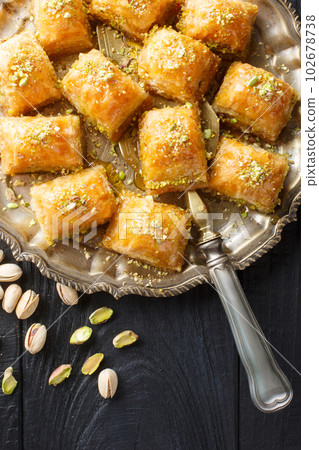 Traditional Middle Eastern Flavors Pistachio baklava or fistikli baklava closeup on the plate. Vertical top view Traditional Middle Eastern Flavors Pistachio baklava or fistikli baklava closeup on the plate. Vertical top view 102678738