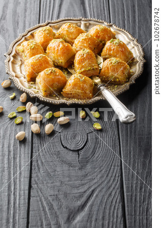 Turkish Baklava with buttery, flaky puff pastry soaked in honey and sugar with tender pistachios stuffed between layers of dough closeup on the plate. Vertical 102678742