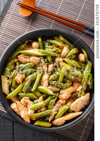 stir fry chicken with asparagus in spicy sauce close-up in a bowl. Vertical top view 102678749
