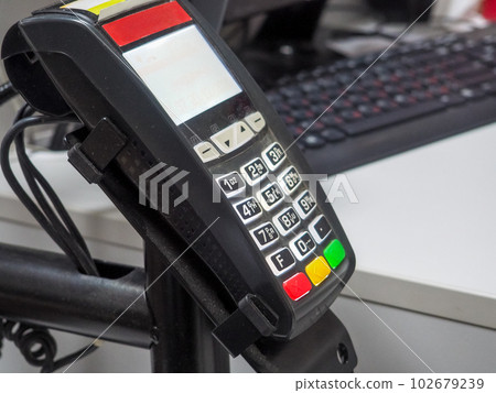 Credit card machine with blurred background with computer and keypad 102679239