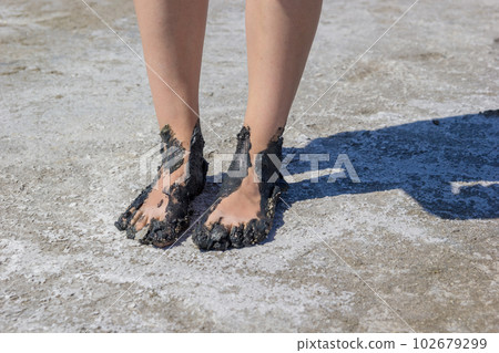 Young woman's feet covered with black dirt 102679299