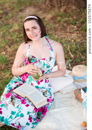 A young woman sitting on a picnic in a park 102679874