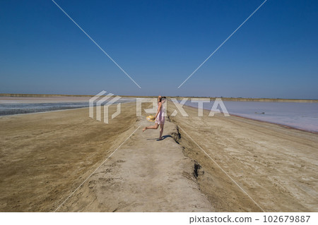 girl in a dress runs barefoot along the shores of a salt lakes 102679887