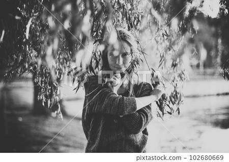 Black and white photo of girl standing among willow branches in a golden sunset Black and white photo of girl standing among willow branches in a golden sunset 102680669