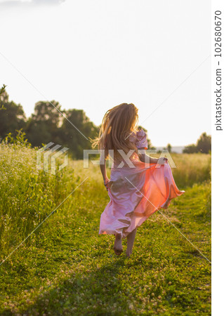 girl running across the field in a pink dress girl running across the field in a pink dress 102680670