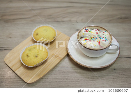 Two muffins with raisins on a wooden tray and a cup of hot chocolate Two muffins with raisins on a wooden tray and a cup of hot chocolate 102680697