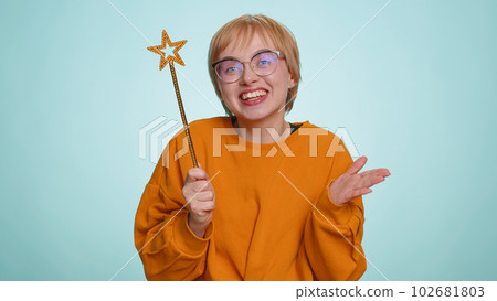 Magician witch young woman gesturing with magic wand making wish come true, casting magician spell 102681803