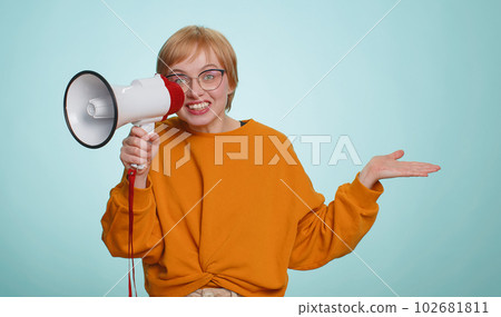 Woman talking with megaphone, proclaiming news, loudly announcing advertisement pointing empty place 102681811