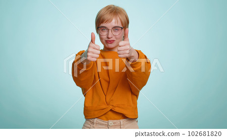 Young woman raises thumbs up agrees or gives positive reply recommends advertisement likes good idea 102681820