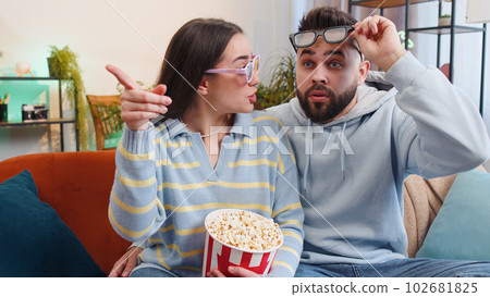 Family man woman on couch eating popcorn, watching interesting TV serial, sport game online at home Family man woman on couch eating popcorn, watching interesting TV serial, sport game online at home 102681825