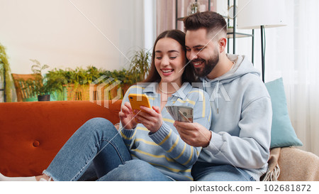 Smiling happy family couple man woman counting money cash use smartphone, income, saves, lottery win Smiling happy family couple man woman counting money cash use smartphone, income, saves, lottery win 102681872