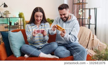 Happy family married couple man woman playing shooter video app games online on smartphone at home 102681876
