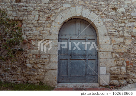 Ancient wooden blue arcade door at a wall of old building 102688666