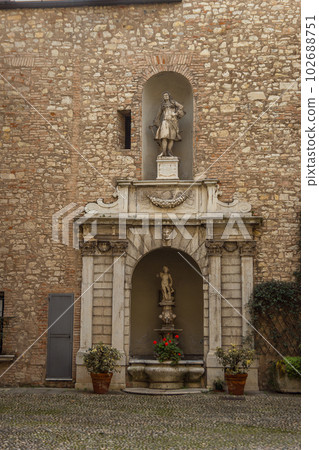 Old sculpture with small fountain and plants and flowers in pots 102688751