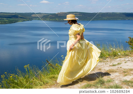A girl in a long dress standing on a cliff by the bay A girl in a long dress standing on a cliff by the bay 102689284