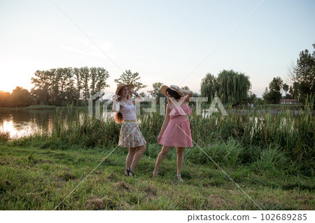 Two girls standing near the lake at sunset 102689285