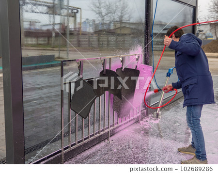 A man covers car mats with pink foam at a self-service car wash A man covers car mats with pink foam at a self-service car wash 102689286