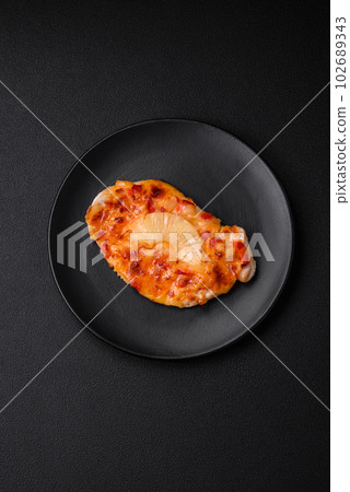 Grilled chicken fillet in the form of a steak with tomatoes, pineapple and cheese 102689343
