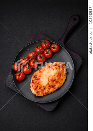 Grilled chicken fillet in the form of a steak with tomatoes, pineapple and cheese 102689374