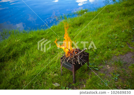 A small folding portable brazier filled with burning wood A small folding portable brazier filled with burning wood 102689830