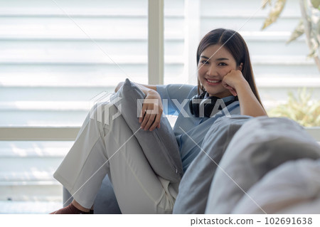Relaxed smiling asian woman sitting on sofa at home 102691638