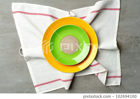 Top view of ceramic plate with table napkin on gray background 102694100