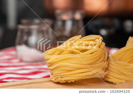 Dry spaghetti on a kitchen counter with cooking utensils 102694320