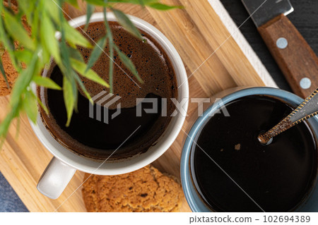 Cup of hot coffee on wooden board on kitchen table Cup of hot coffee on wooden board on kitchen table 102694389