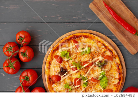 Delicious pizza on gray wooden background top view Delicious pizza on gray wooden background top view 102694498