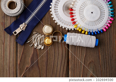 Threads and sewing accessories on brown wooden table Threads and sewing accessories on brown wooden table 102694500