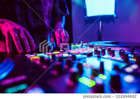 Close up of DJ hands on dj console mixer during concert in the club 102694682