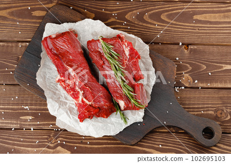 Beef tenderloin on wooden board on wooden table Beef tenderloin on wooden board on wooden table 102695103