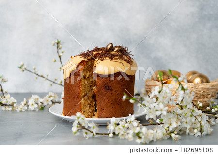 Cut Easter cake on plate decorated with spring flower branches Cut Easter cake on plate decorated with spring flower branches 102695108