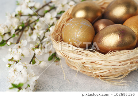 Easter eggs painted in gold in nest on table Easter eggs painted in gold in nest on table 102695156