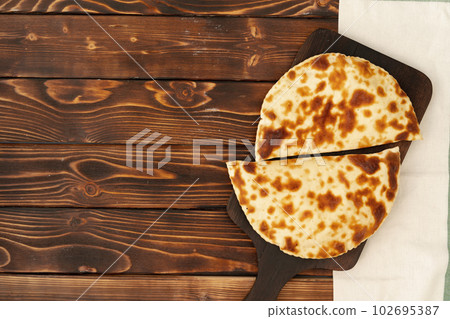 Baked homemade flatbread on wooden background close up 102695387